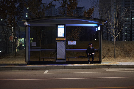 晚上坐在公交站台等车的男性图片