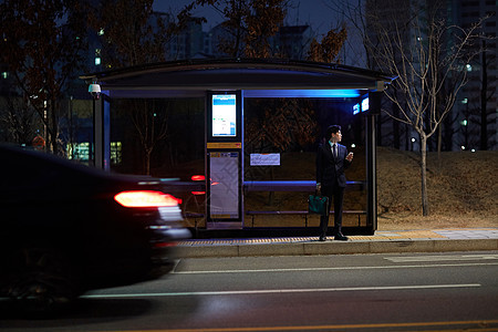夜晚公交站台等车的青年男性户外的高清图片素材