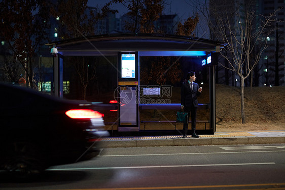 夜晚公交站台等车的青年男性图片