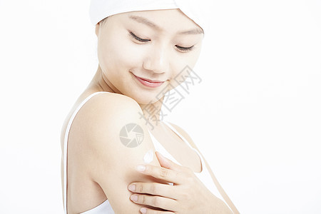 女青年低头涂抹手臂的乳液图片