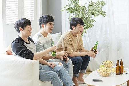 在客厅享受啤酒零食的男人们图片