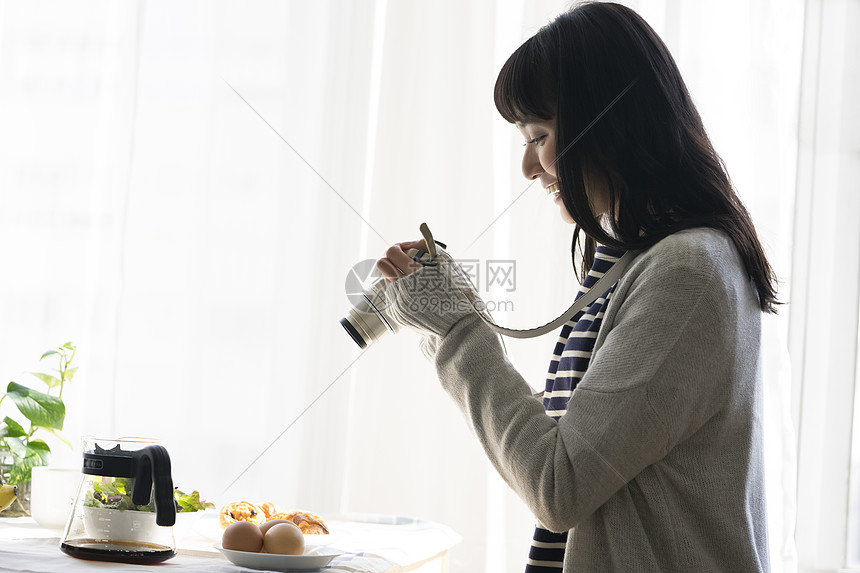 年轻女子拿着相机拍食物照片图片