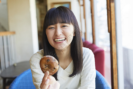 咖啡馆拿着面包微笑的年轻女子图片