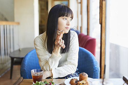 咖啡馆吃着面包的女青年图片