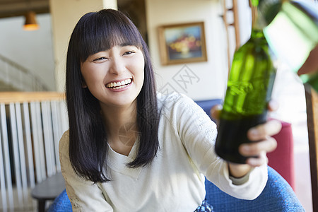 拿着瓶装啤酒微笑的年轻女子图片