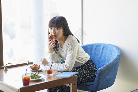 咖啡馆吃着面包的年轻女子图片