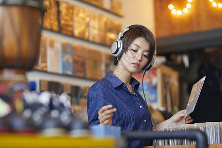 年轻美女唱片店带着耳机听音乐高清图片