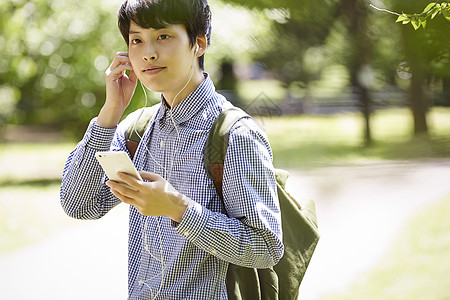 拿着手机戴上耳机的男子图片