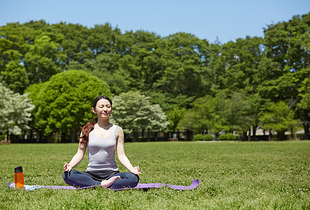 公园草坪上做瑜伽的女性图片