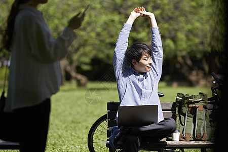 长凳上拉伸双臂的男青年背景图片