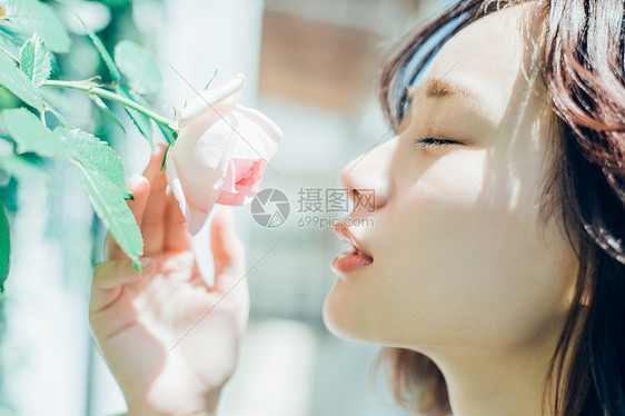 细闻鲜花的青年女性图片