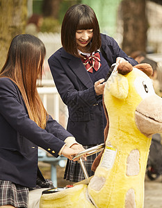 穿制服的女孩在动物园玩耍图片