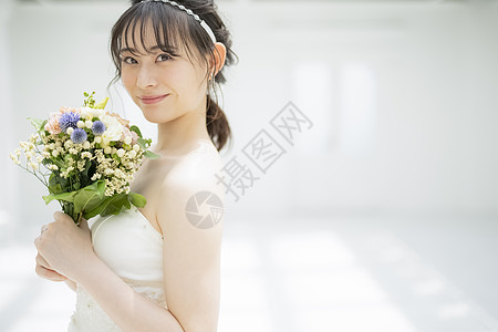 年轻新娘拿着手捧花微笑图片