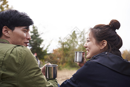 野外露营的年轻情侣聊天喝咖啡图片