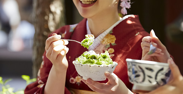 在茶馆穿桃红色和服吃甜点的妇女图片