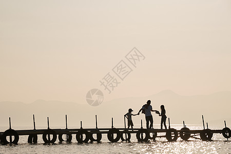 儿童剪影素材暮色下一家三口在湖面桥上的游玩背景