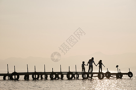 暮色下一家三口在湖面桥上的游玩高清图片