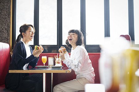 餐厅里吃汉堡聊天的闺蜜好友图片