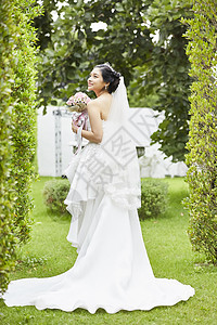 新娘穿着纯白婚纱手拿捧花图片