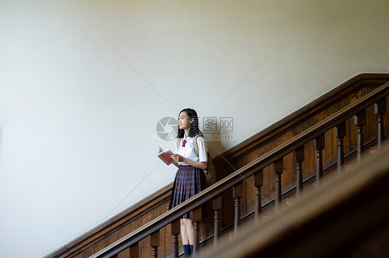 穿校服的女学生在楼梯上拍照图片