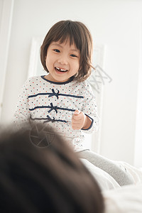 微笑休假年轻的女孩父母和孩子在床上玩图片