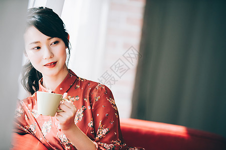 假日坐在靠窗的沙发上喝茶的女人图片