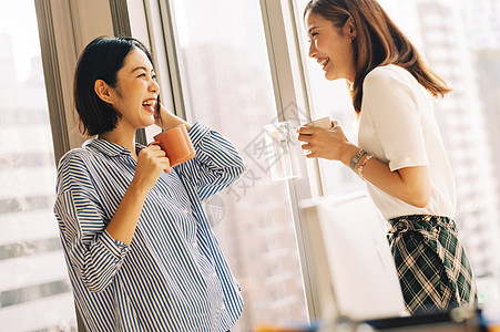 在窗户旁喝咖啡休息聊天的职场女性图片