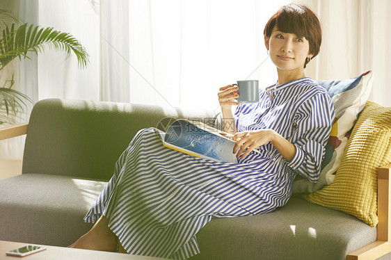 居家沙发上喝咖啡看杂志的成年女性图片