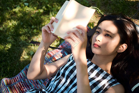 躺在草坪上阅读的女青年背景