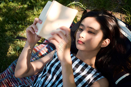 躺在草坪上阅读的年轻女子背景