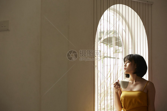窗边喝咖啡享受下午茶的女青年图片