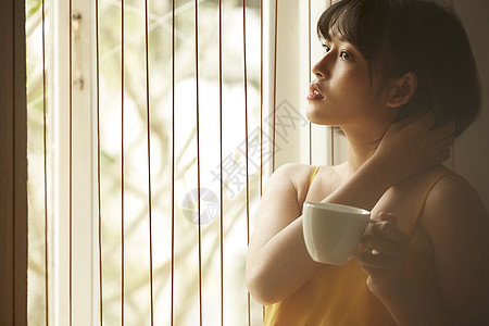 窗边拿着咖啡的女青年图片