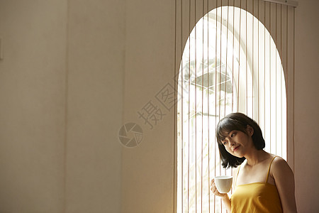 窗边拿着咖啡的文艺女青年图片