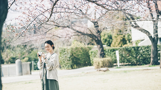 拍摄爱好享受樱花拍照片的春天妇女图片