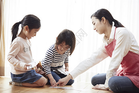 老师和孩子坐在地板上玩纸牌图片