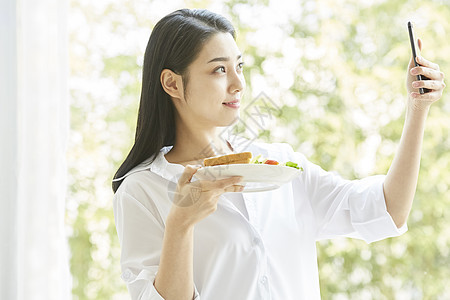 拿手机拍食物的居家女孩图片