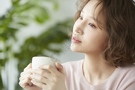 捧着咖啡思考的年轻女子图片