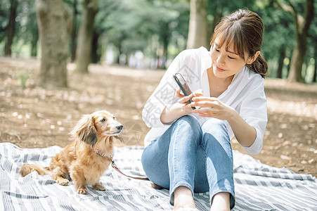 年轻女子拿着手机拍宠物狗图片