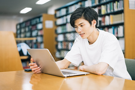 电脑学生在图书馆阅读的年轻人背景