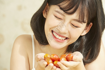 捧着小番茄微笑的年轻女子图片