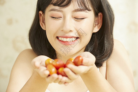 捧着小番茄微笑的年轻女子图片