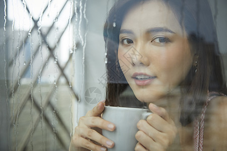 下雨天喝咖啡的年轻女孩图片