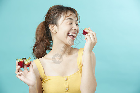 可爱女孩开心举着草莓脸部护理高清图片素材