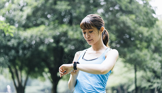 低头看着手表的运动女性图片