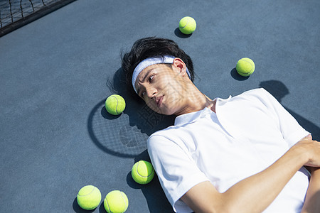 躺在网球场地上休息的青年男性图片