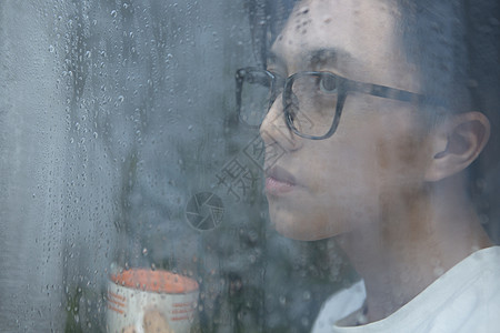 下雨天看向窗外的青年男子图片