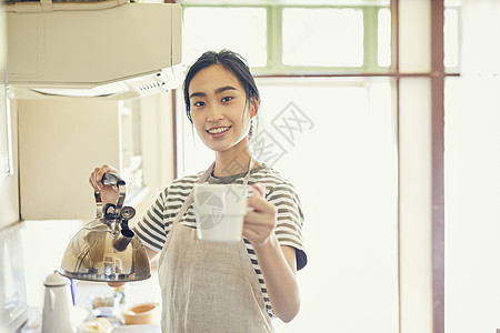 拿着烧水壶的青年女子图片