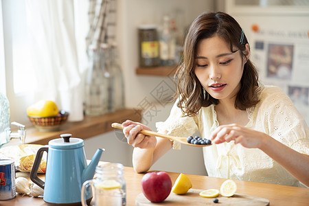 居家拿着勺子吃蓝莓的年轻女子图片