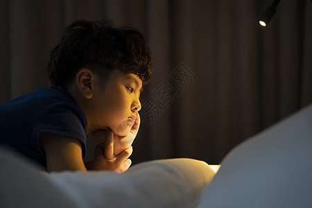夜晚睡前阅读的小男孩图片
