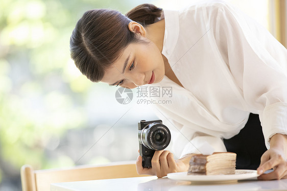 相机拍摄食物照片的年轻女子图片